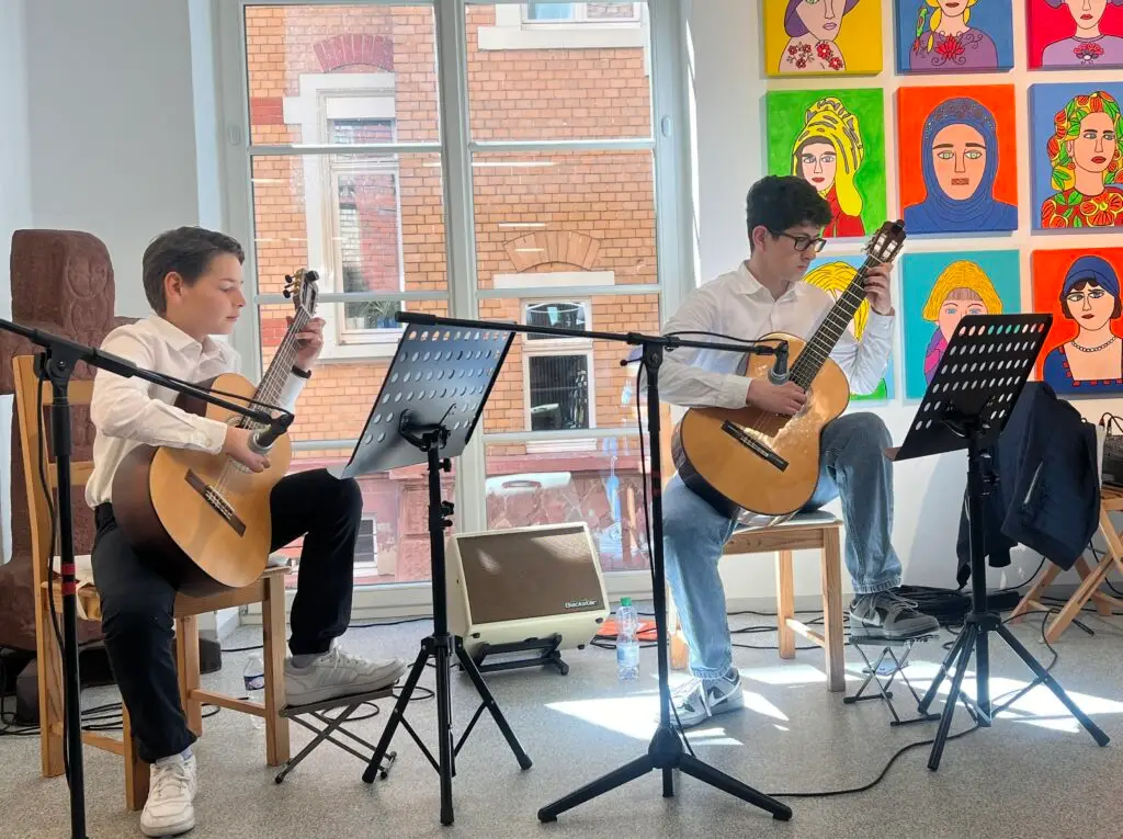 Jugendliche beim gemeinsamen Gitarrenunterricht zur Vorbereitung auf den nächsten Auftritt.